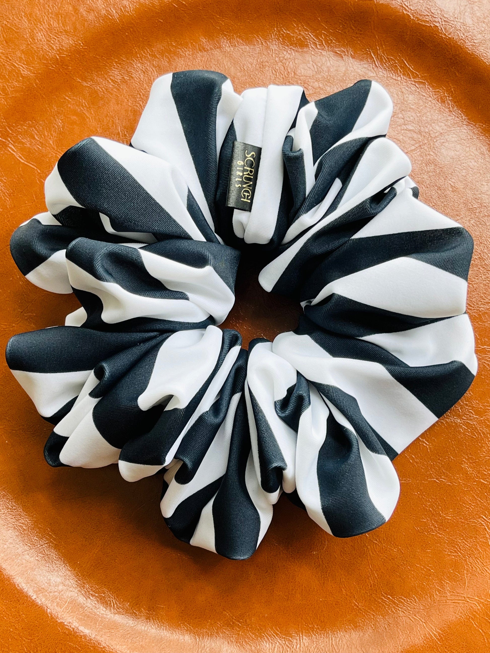 A black and white striped scrunchie on a orange surface.