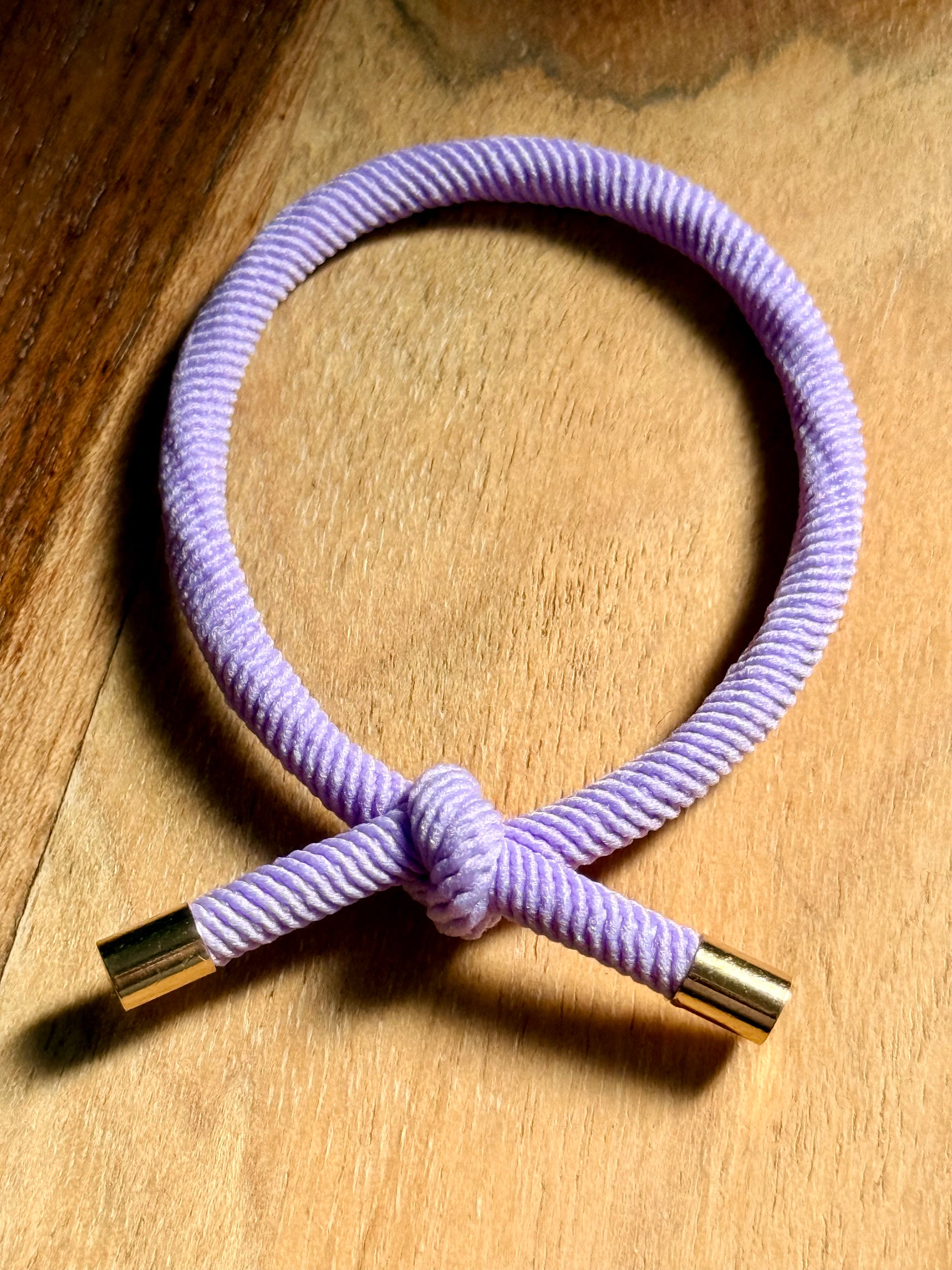 Purple hair tie with gold ends on a wooden surface