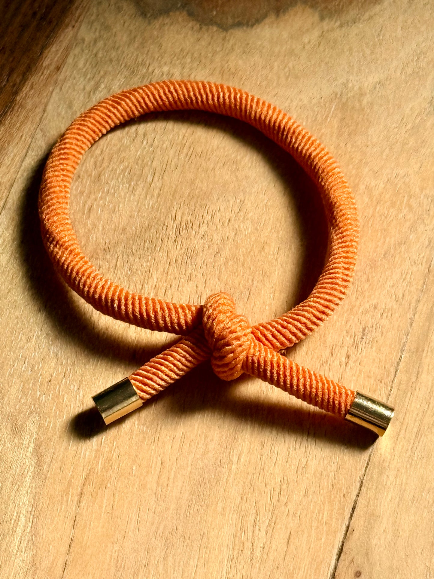 Orange braided cord with metal connectors on a wooden surface
