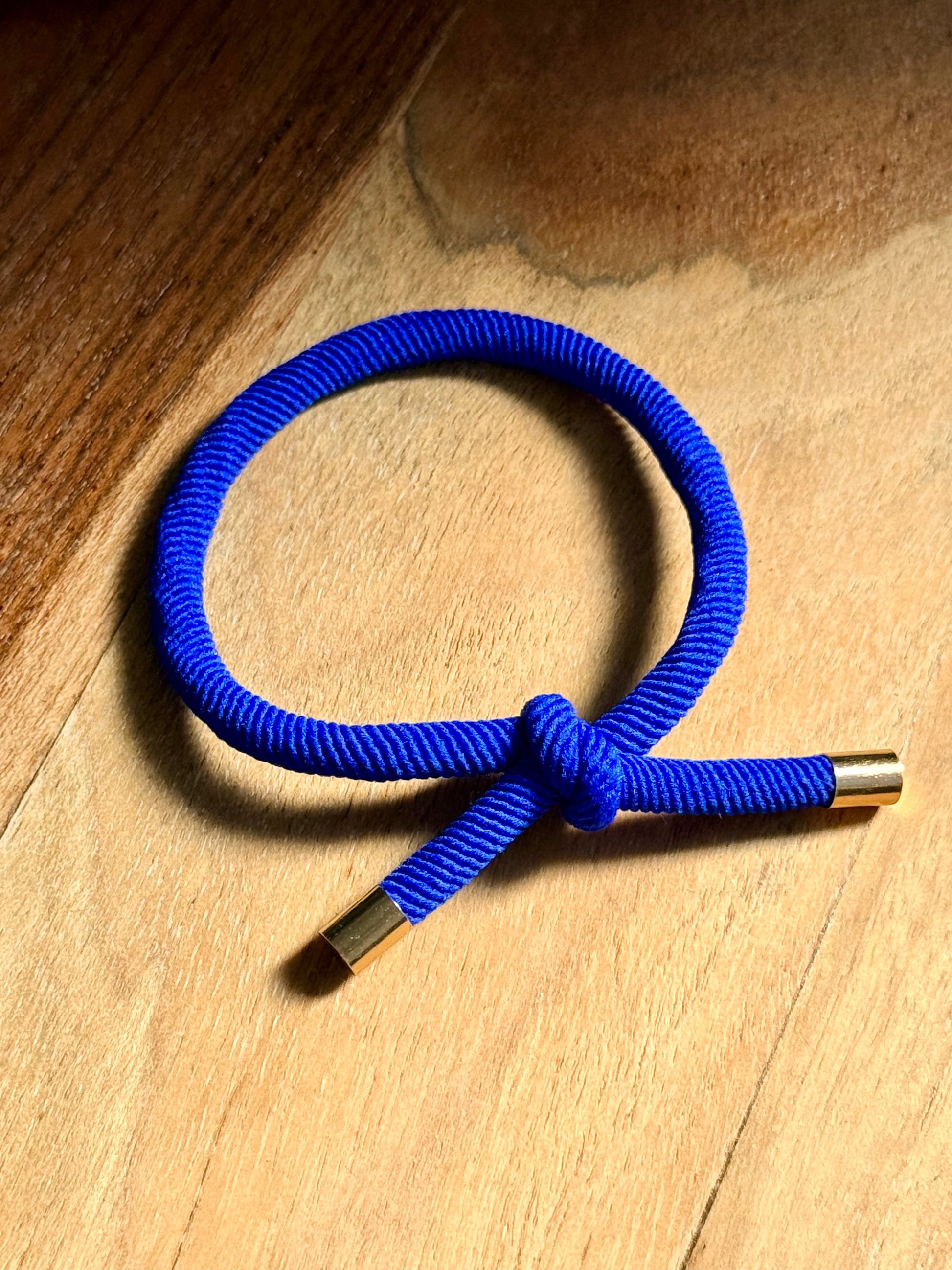 Blue cord with gold ends on a wooden surface