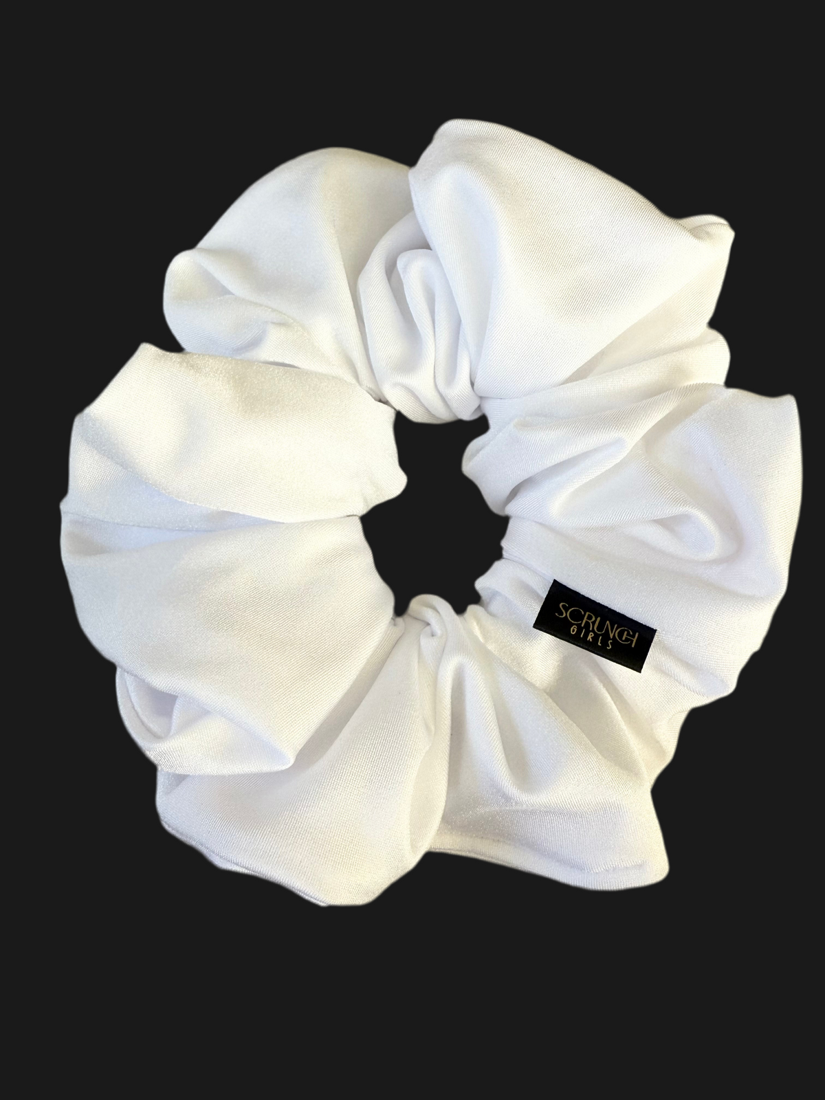 White scrunchie with a brand label on a black background